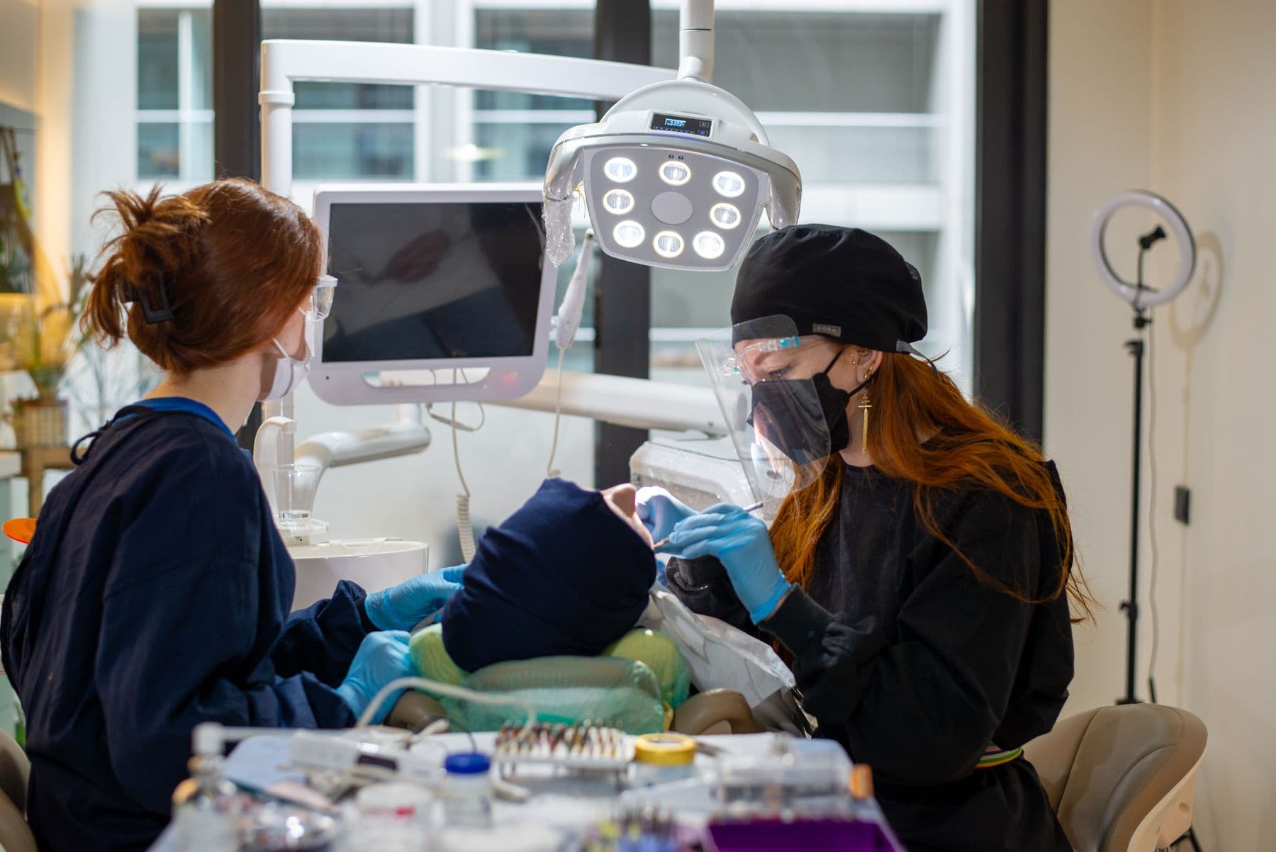 A dentist and assistant treating a patient in a bright dental clinic